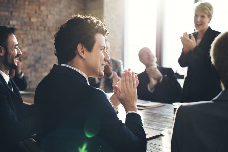 Photo of a group of people sitting at a table clapping